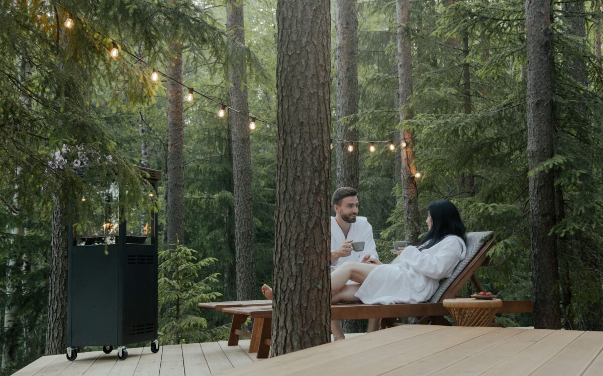 Casal em roupões aproveitando relaxamento em espreguiçadeiras em um cenário tranquilo de floresta