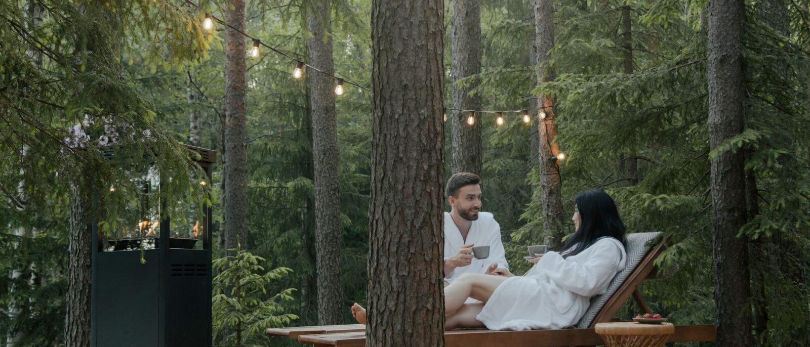 Casal em roupões aproveitando relaxamento em espreguiçadeiras em um cenário tranquilo de floresta