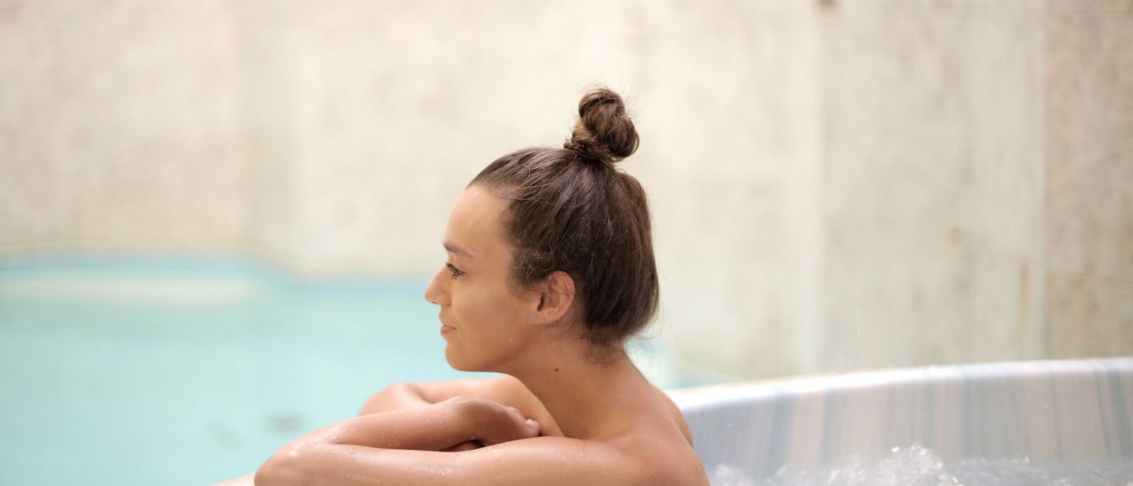 Mulher aproveitando um momento relaxante em uma banheira de água quente interna, potencializando bem-estar e lazer