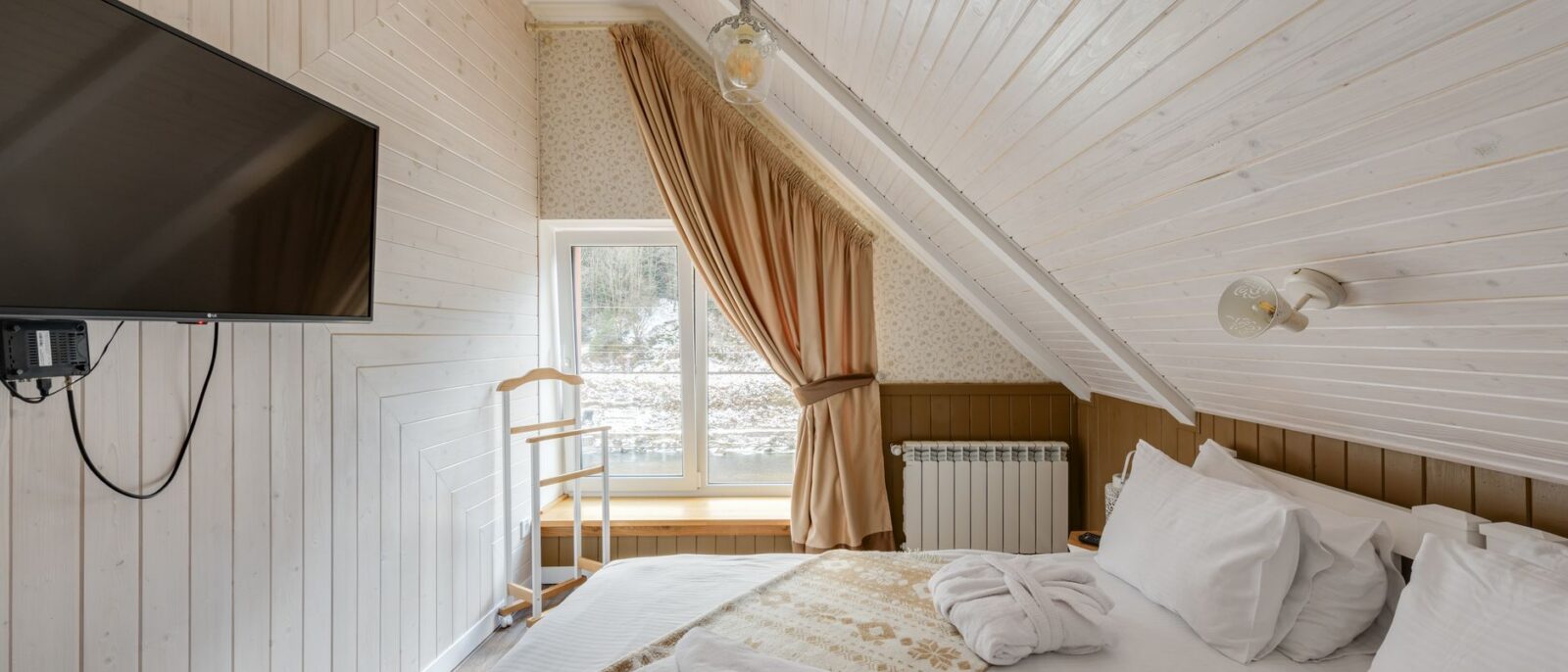 Quarto aconchegante no sótão com design moderno, acabamento em madeira e TV