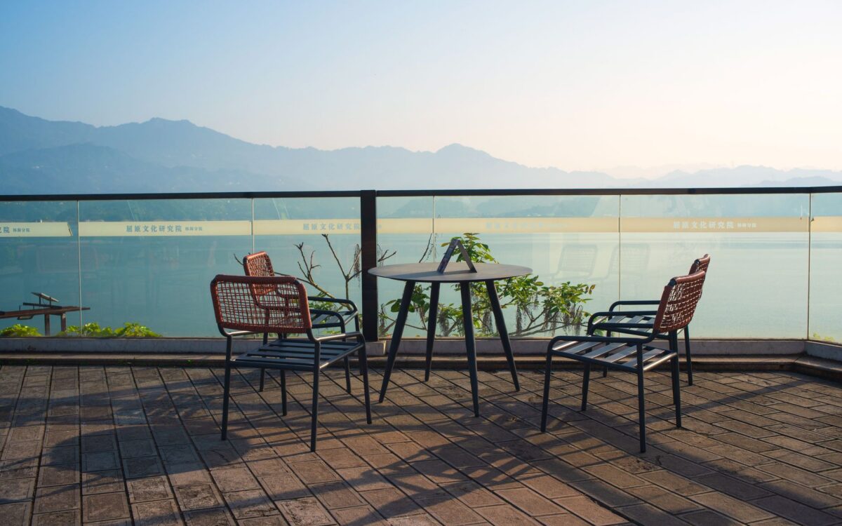 Terraço externo tranquilo com cadeiras com vista para montanhas e água