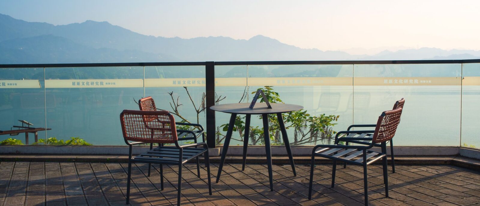 Terraço externo tranquilo com cadeiras com vista para montanhas e água